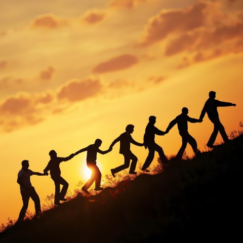 Männer halten sich an den Händen und gehen im Sonnenuntergang einen Hang hinauf
