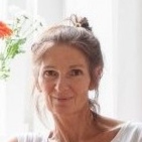 Frau mit hochgesteckten dunkelblonden Haaren, lächelt